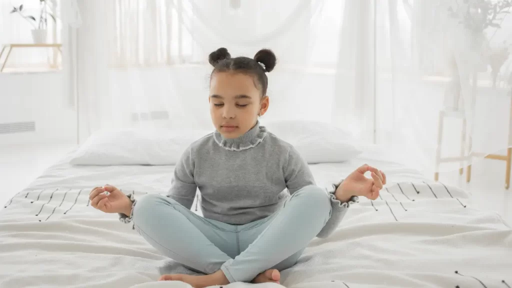 Criança sentada com os olhos fechados praticando respiração consciente, simbolizando calma, foco e alívio da ansiedade infantil por meio do método C.A.L.M.A.