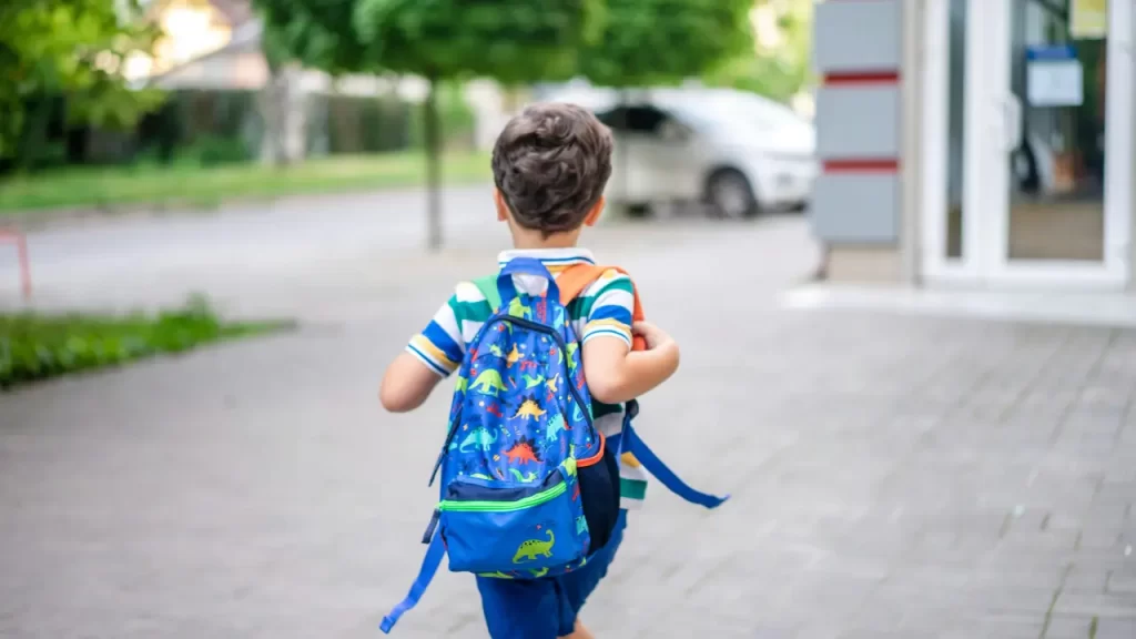 Criança sorridente com mochila indo para a escola, representando autoconfiança, bem-estar e superação da ansiedade infantil com apoio familiar.